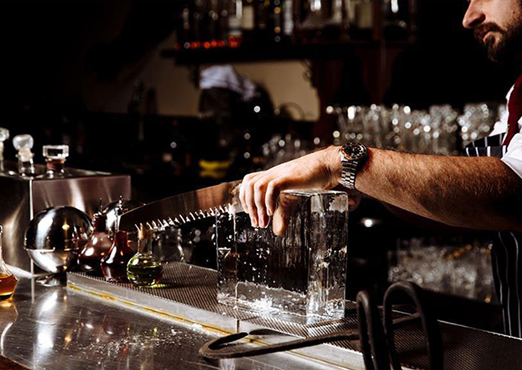 A profesional barman cutting a block of ice - The Spirit Lab Advanced Mixology course